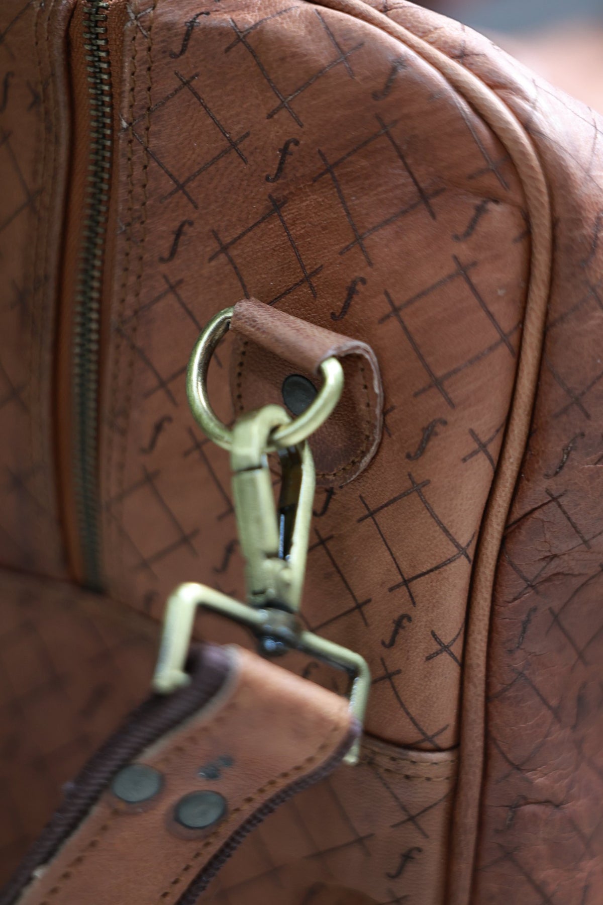 Brass handle fitting on the embossed full-grain leather of the Orion duffel