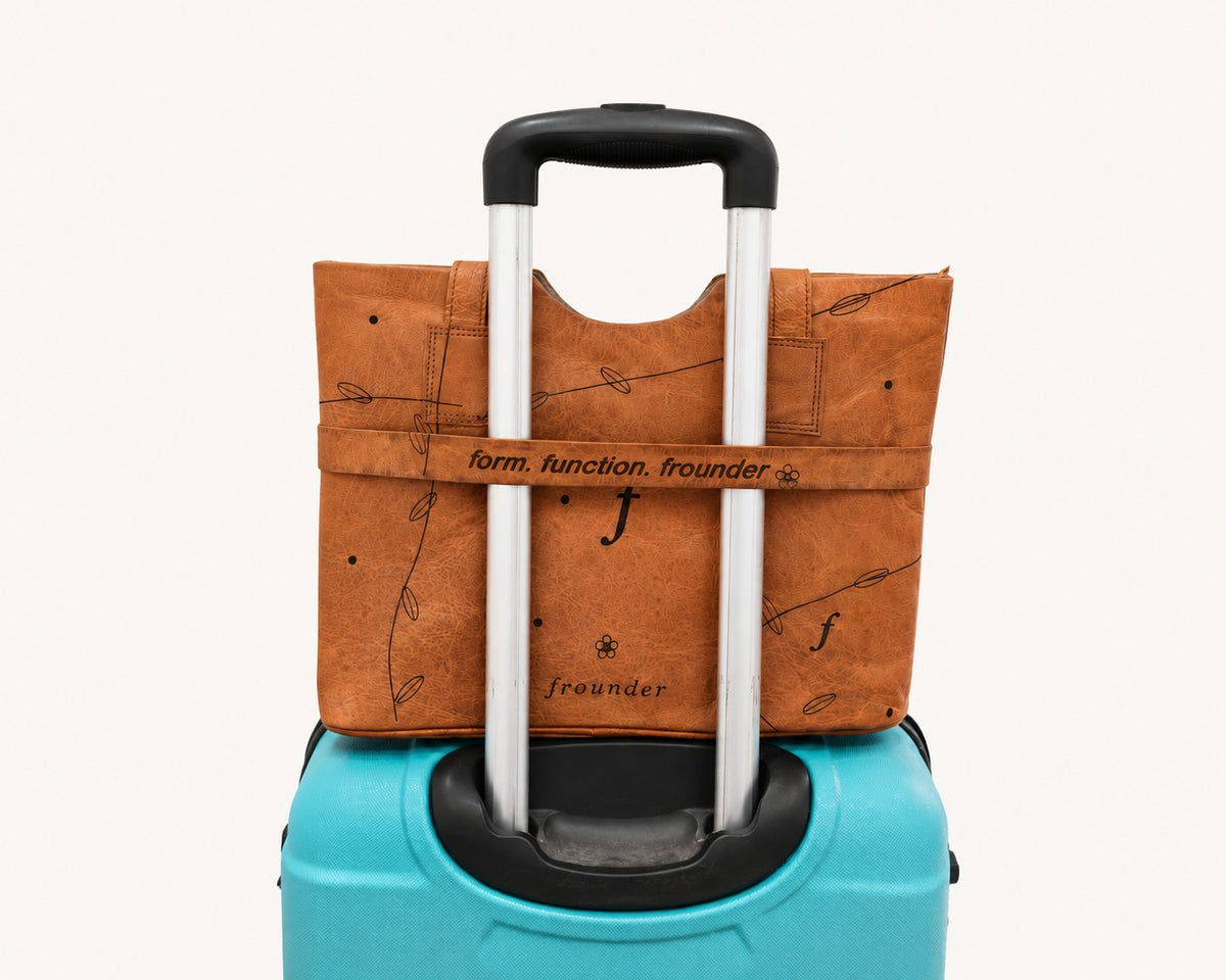 Frounder Aurora leather work tote resting on a suitcase for travel