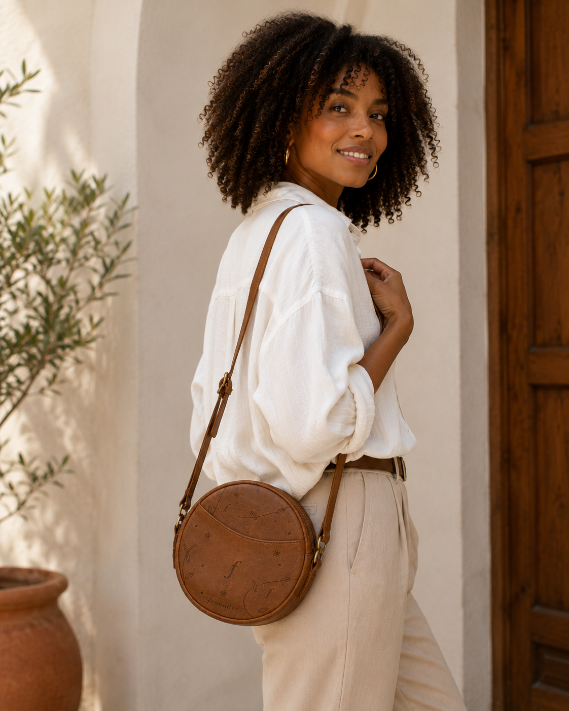 Woman carrying a Frounder Orbit round leather crossbody bag outdoors