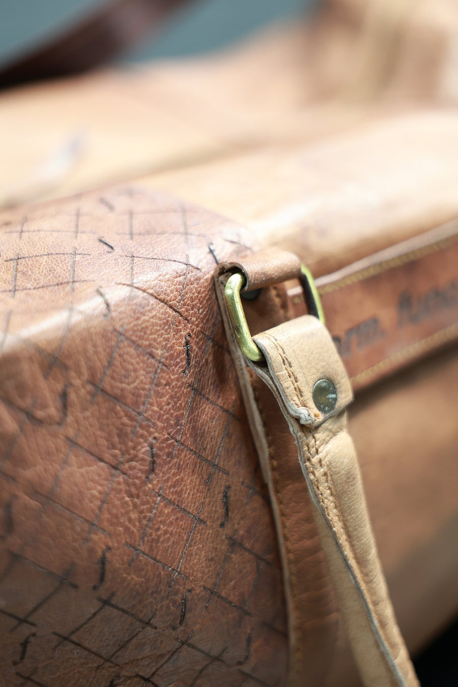 Solid brass D-ring and clip on the engraved leather side panel of the Orion duffel