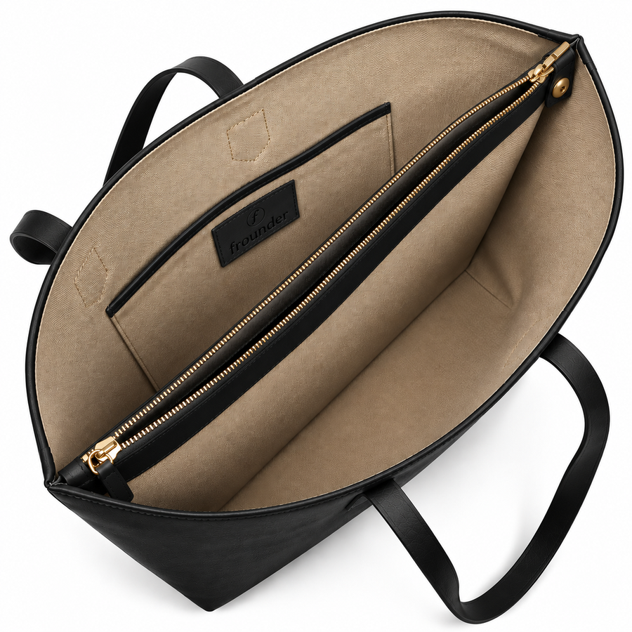 The Altair tote in black, open from above, showing the cotton lining, the solid brass zip and the Frounder label inside.