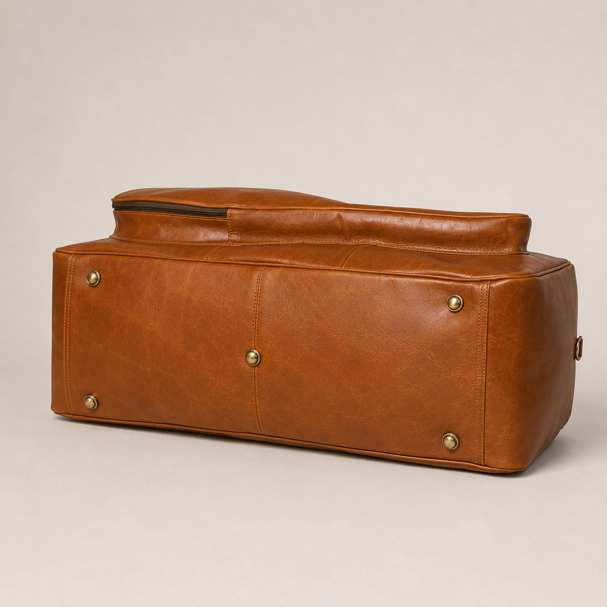 Frounder Henry tennis duffle in brown leather with solid brass studs, shown at an angle