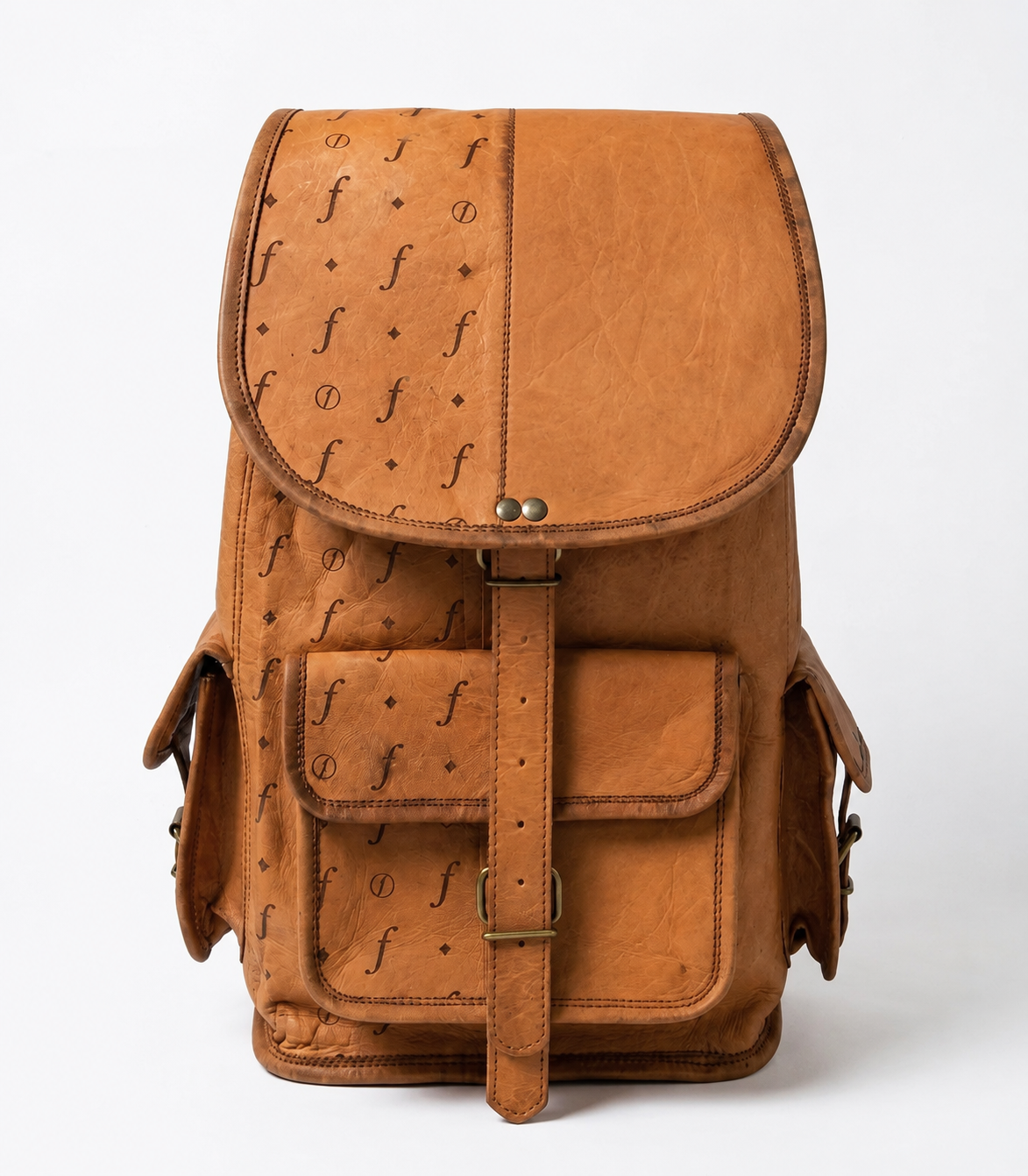 A tan leather backpack with a textured ostrich-style print on the flap and front pocket, featuring brass-tone hardware and a central buckle strap, photographed against a clean white background.