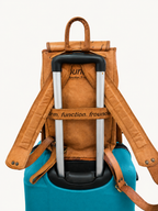 Brown leather backpack with a blue suitcase underneath on a white background